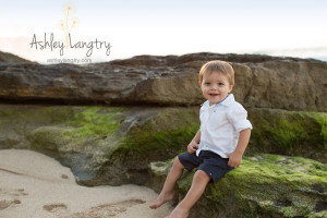 baby boy poses on green rock