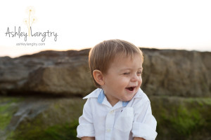 boy laughs and giggles while on rock