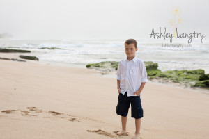 by poses in front of green rocks in white shirt