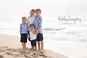 brothers pose on beach in blue and white shirts