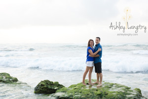 couple pose on green rock in blue shirts