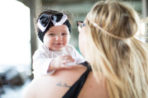 baby girl looks over moms shoulder