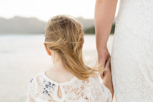 mom and daughter hold hands on beach