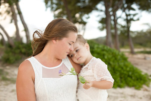 mom holds daughter on beach with flower