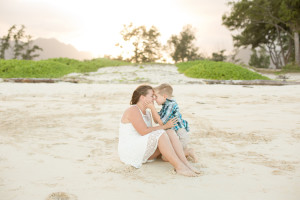 son holds moms cheeks on beach