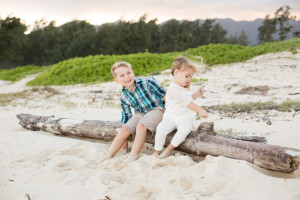 kids sit on log on beach