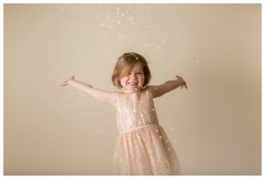 a little girl poses for photos with gold glitter with ashley langtry photography in portland maine