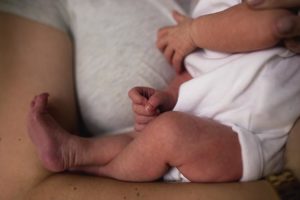 close up image of babies legs while snuggled in moms arms