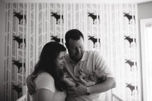 black and white image of family in nursery with moose wallpaper
