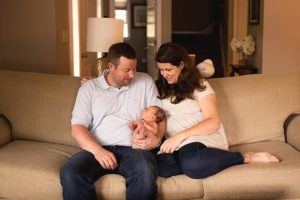 new family snuggled up on the couch with newborn baby