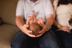 front view of a baby laying down in dads hands
