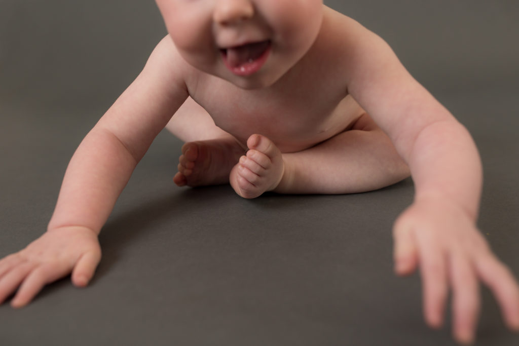 baby crawling on grey backdrop