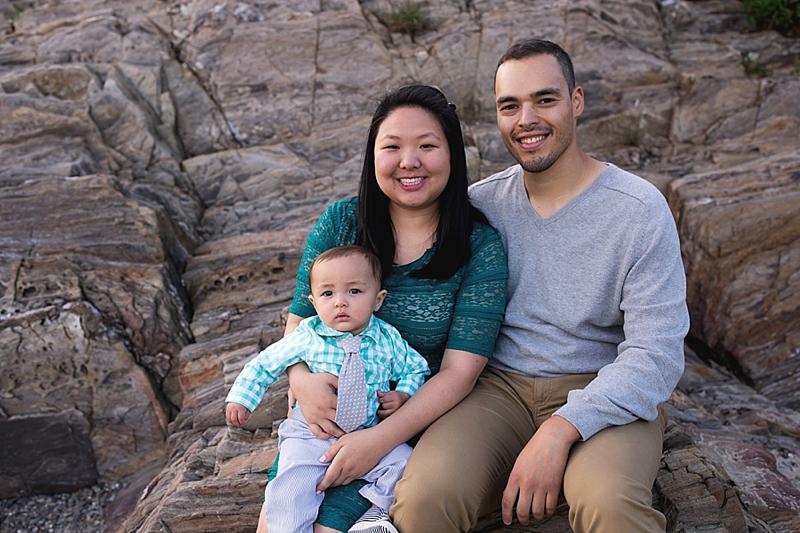 family sits on rocks at lands end beach