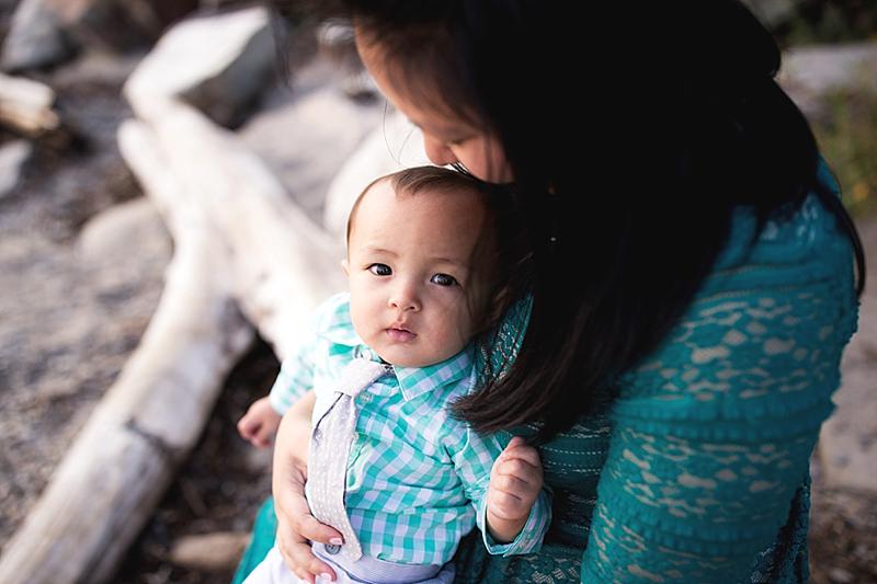 baby sits with mom on beach
