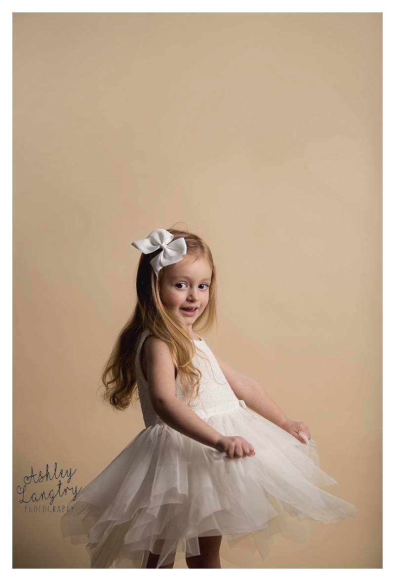 little girl twirls on a creme backdrop