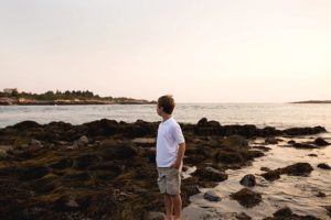 little boy boy standing on the rocks in harpswell maine