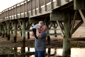 dad kisses baby boy at the beach