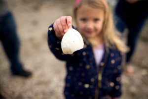 little girls shows her shell on the beach