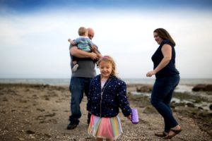 family plays together at the beach in spring
