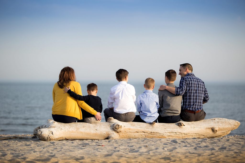 family sits together on beach