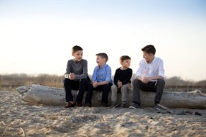 brothers sit on driftwood