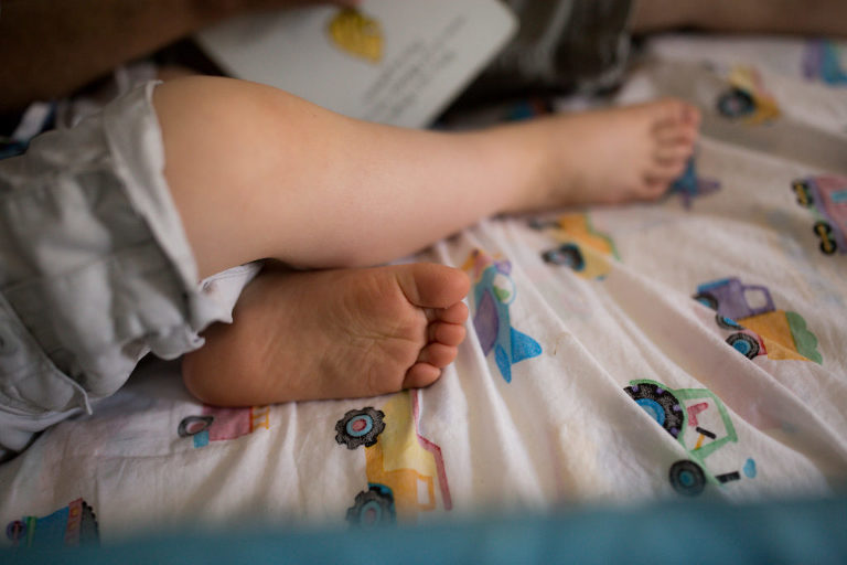 little boy toes as he reads with dad