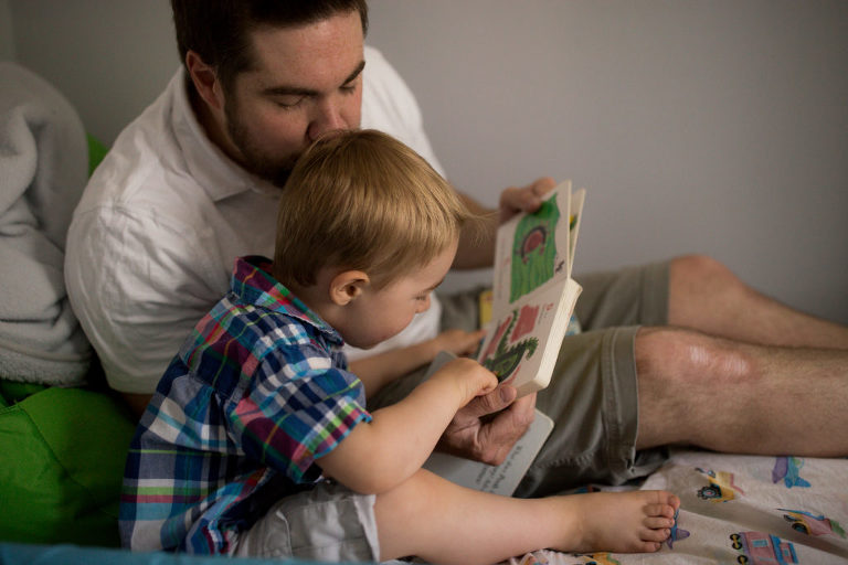 dad kisses son as they sit and read