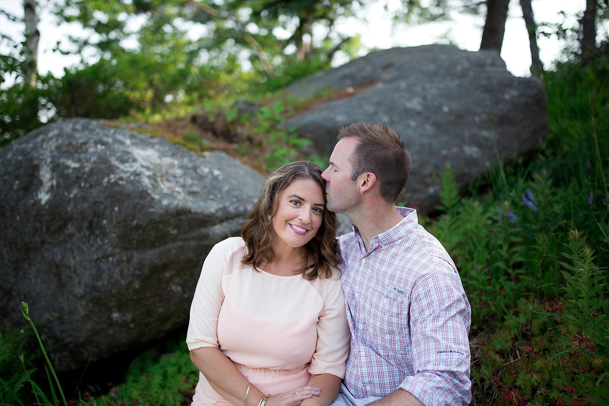man kisses woman on rocks in Boothbay Maine