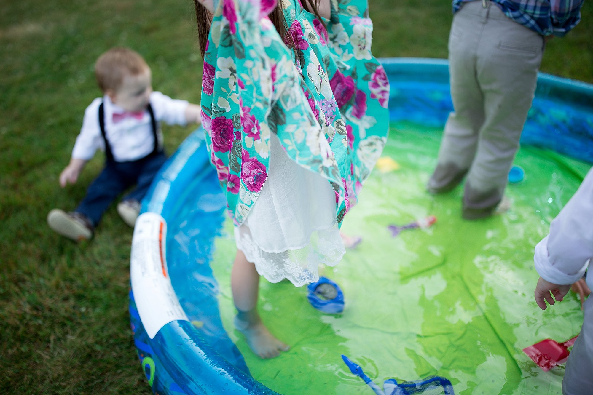 girl in flower dress plays in kiddie pool