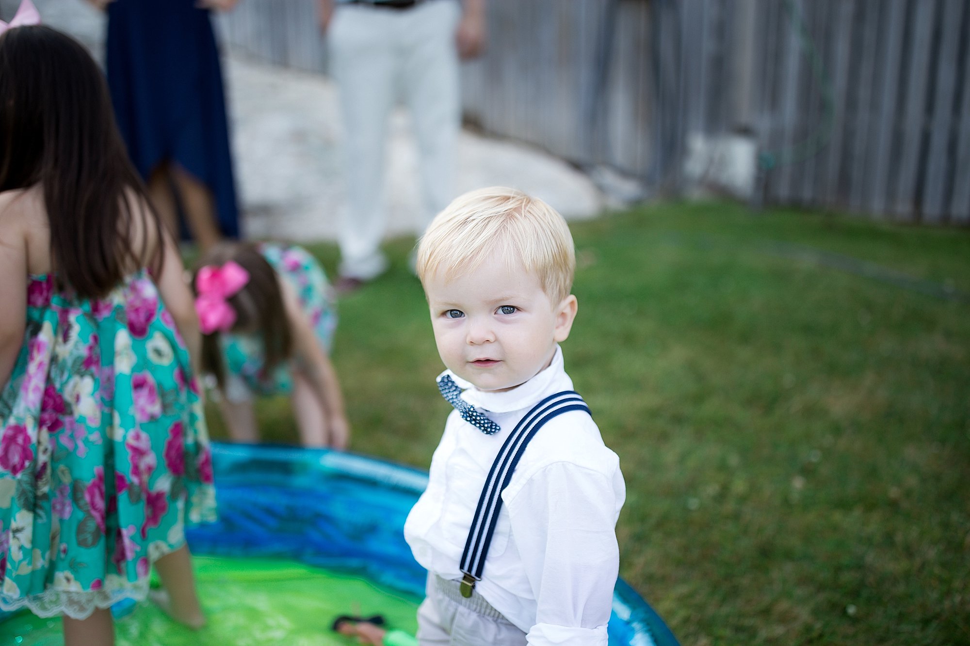 boy in bowtie plays in kiddie pool