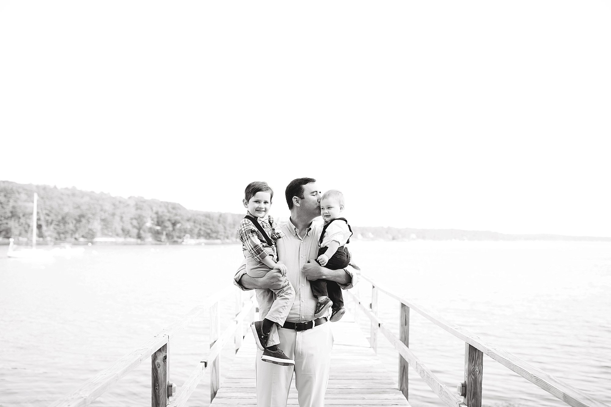 Dad holds his sons on a pier 