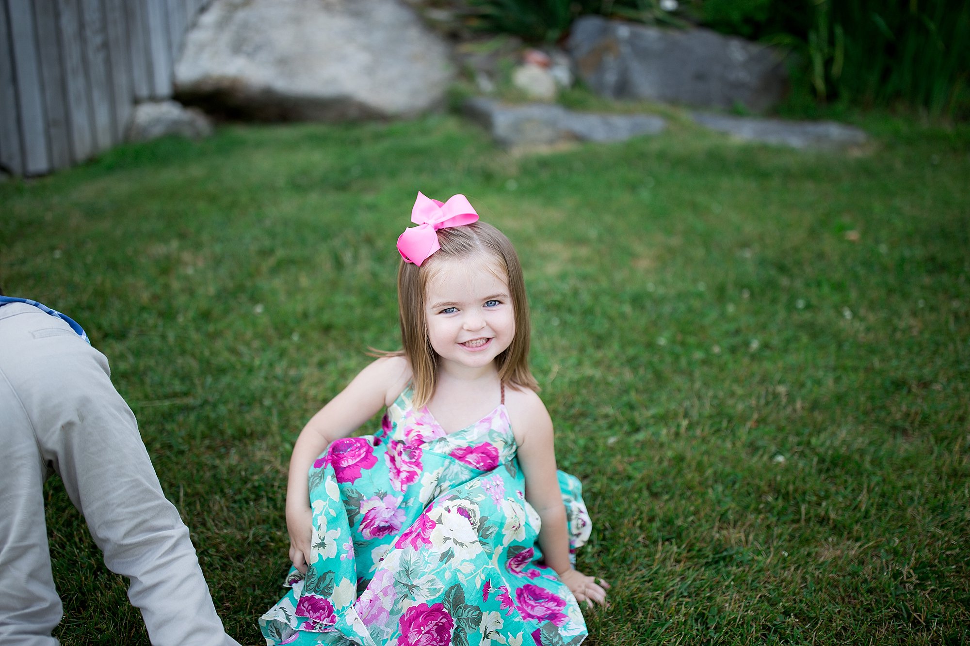 Girl in flower dress smiles in the grass