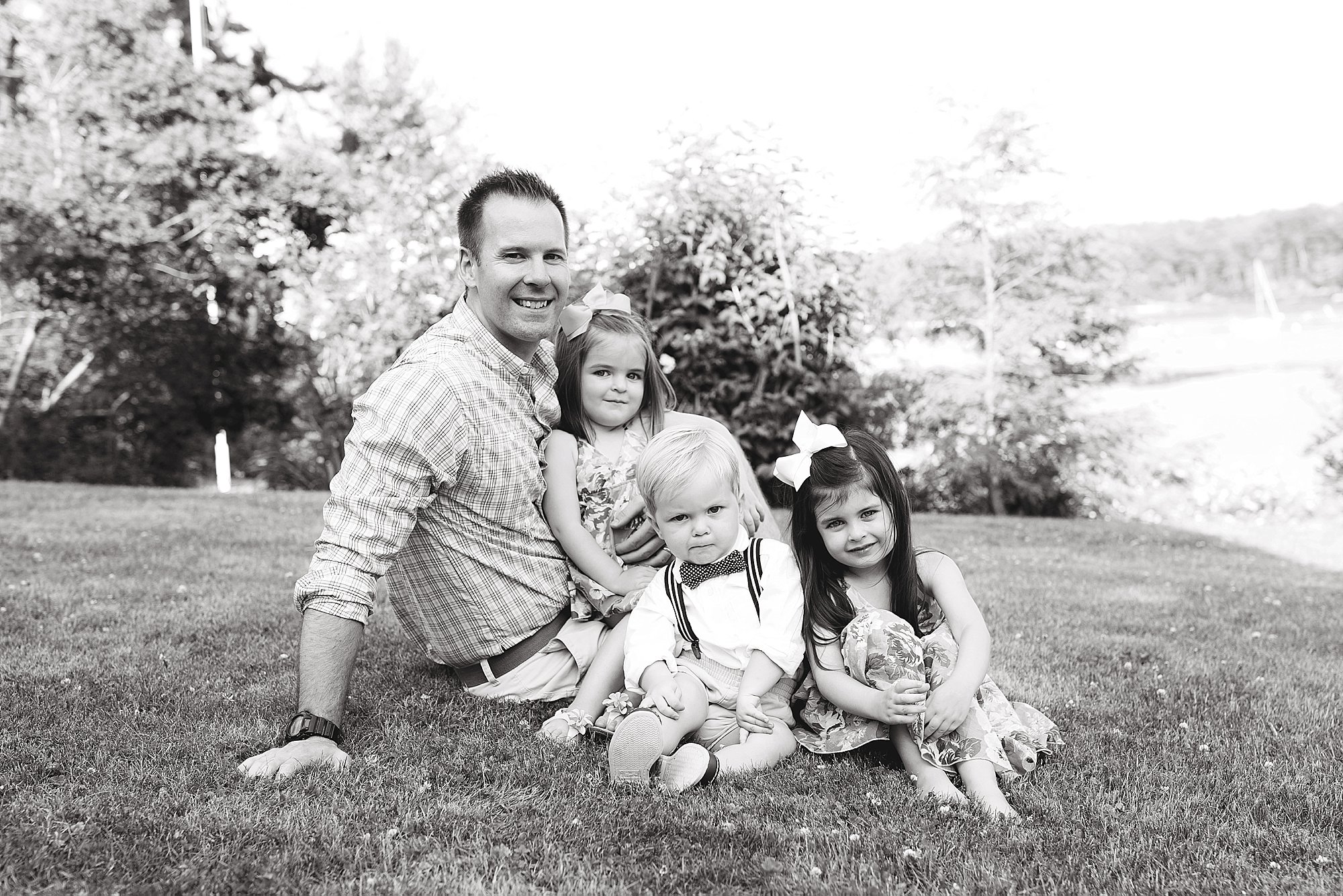 Dad sits with kids in the grass.