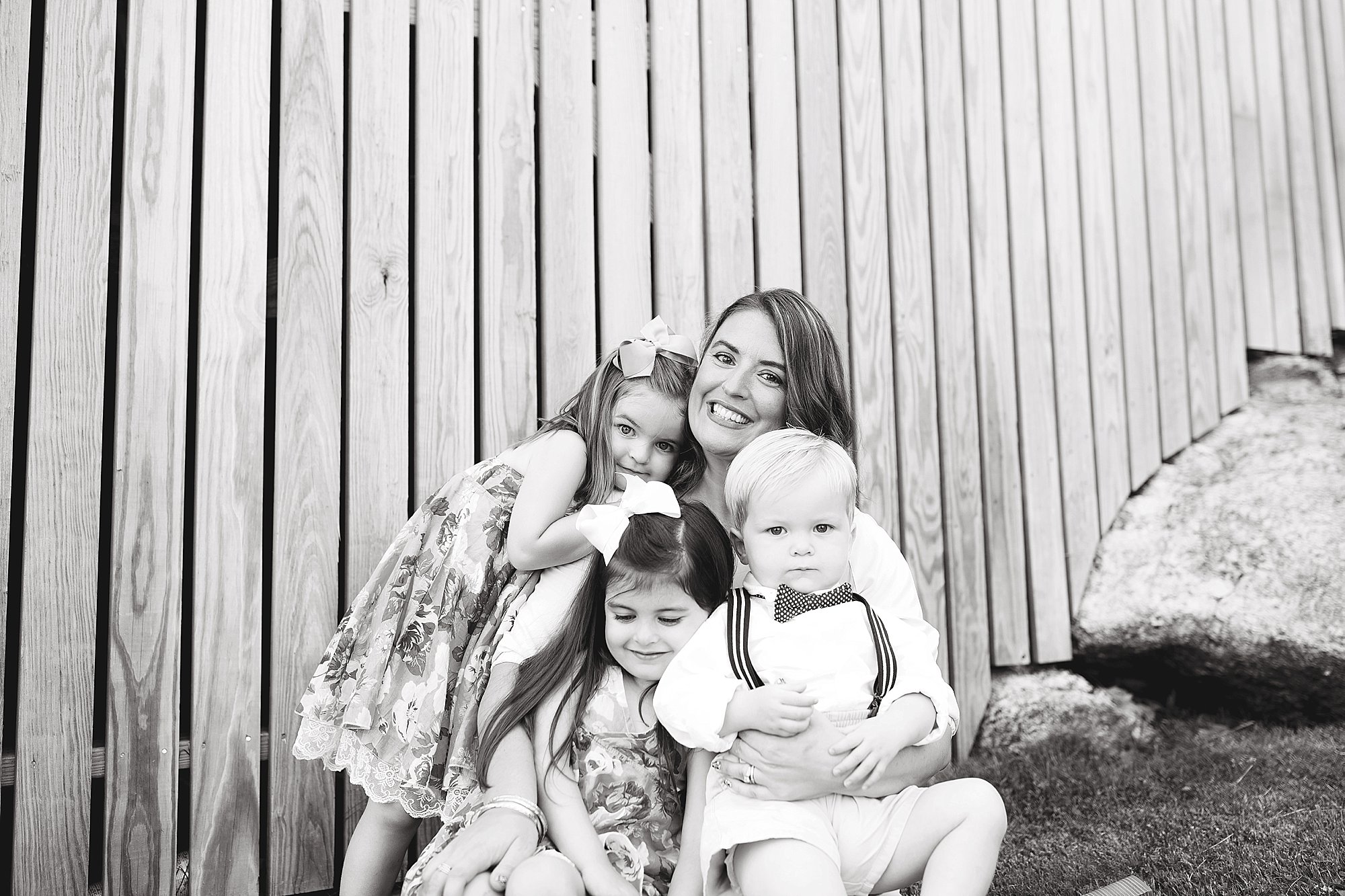 Mama sits with kids in front of wooden backdrop