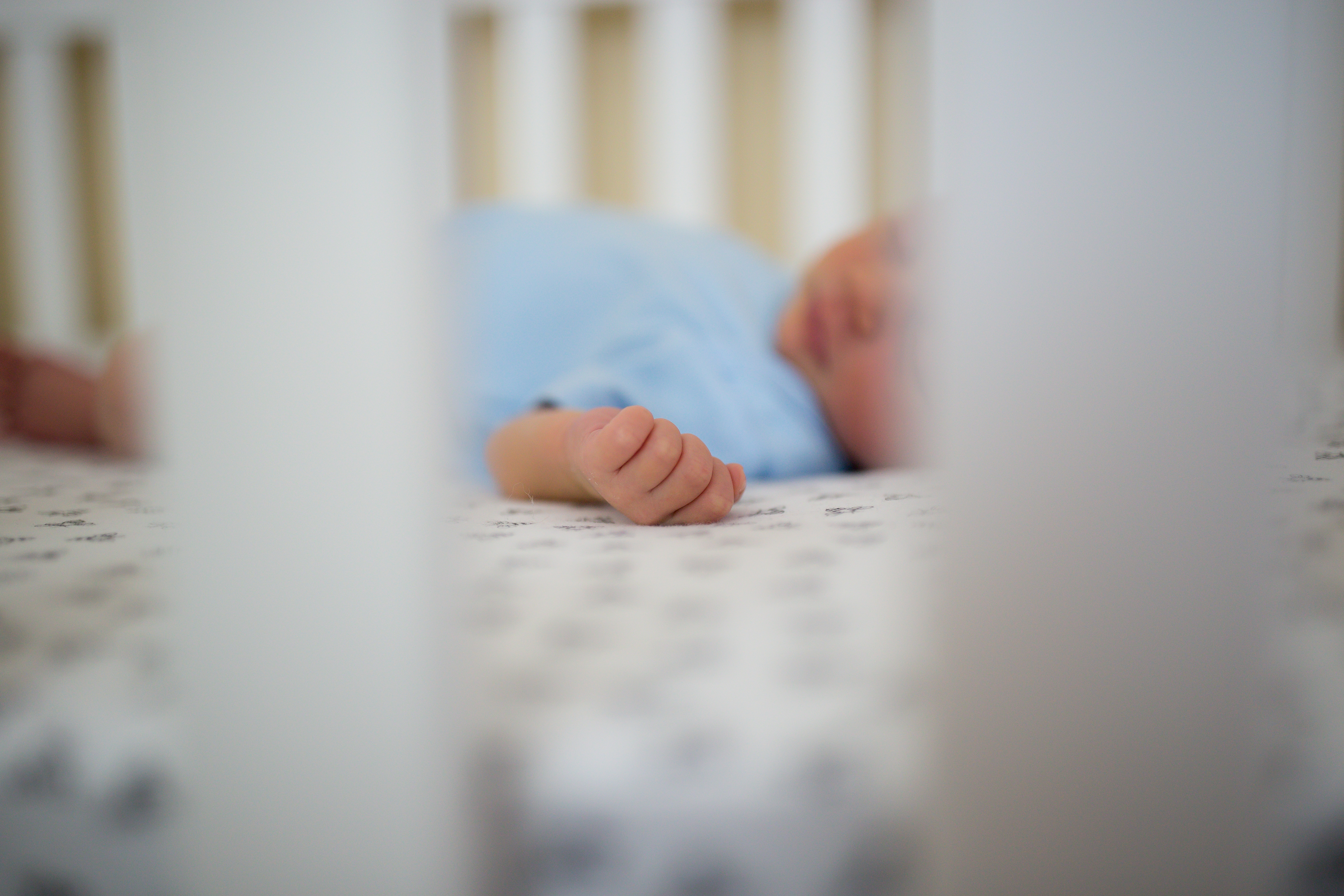 close up of baby hand in crib