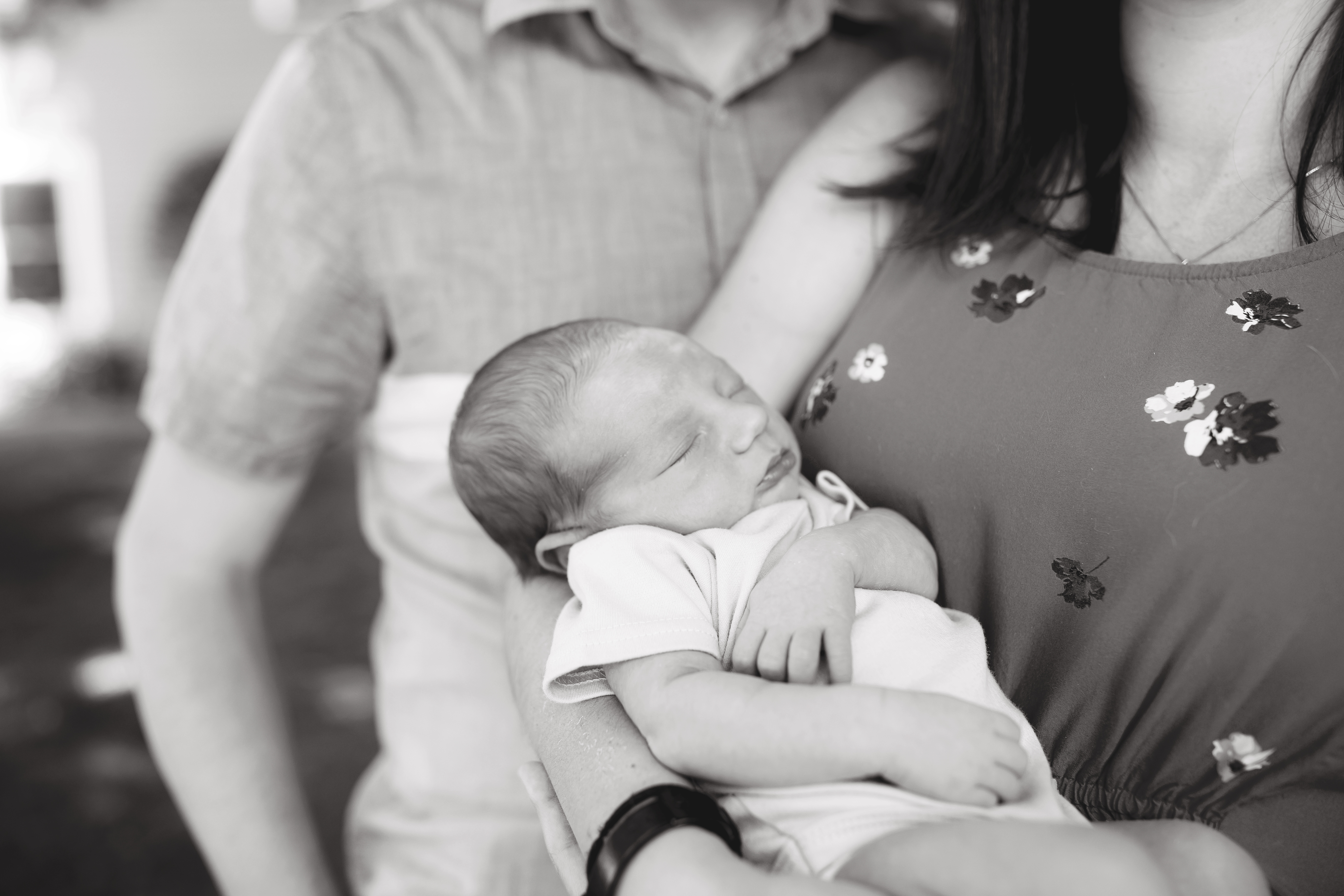 mom and dad pose for a black and white image with their newborn son
