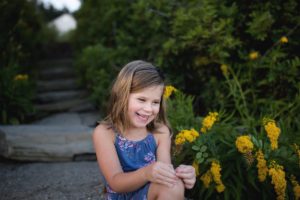 girl smiles by flowers