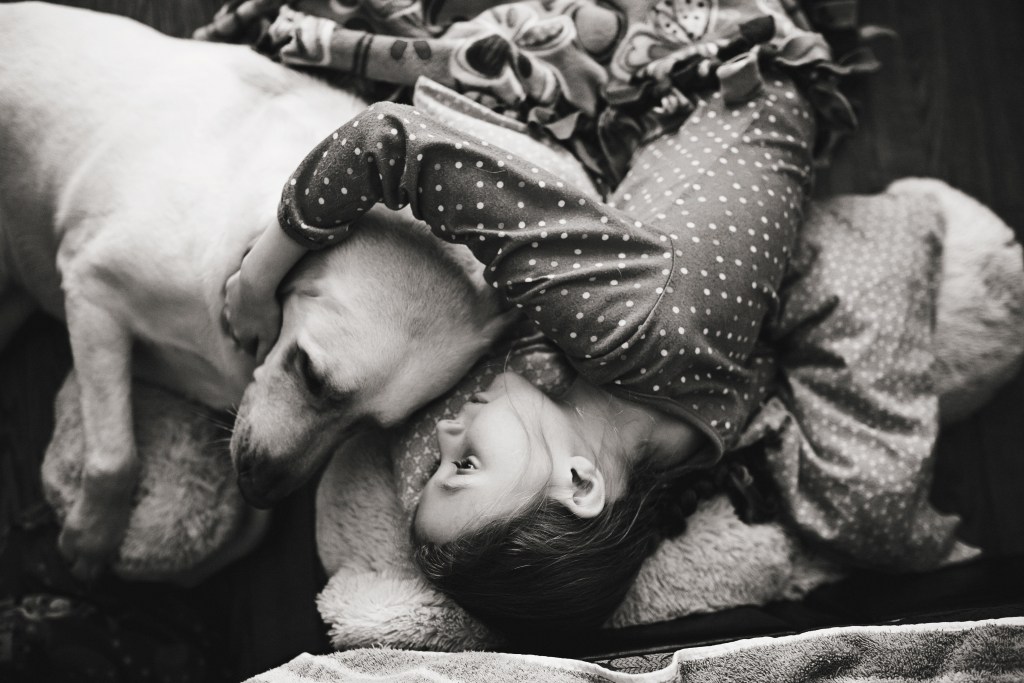 girl snuggles yellow lab